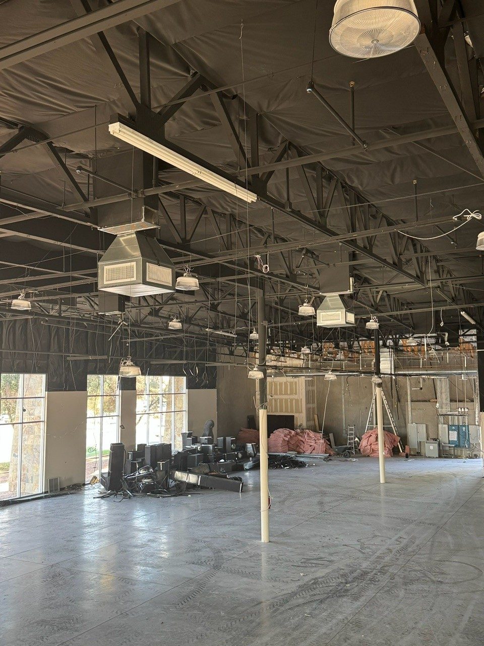 Overhead ductwork and air distribution installed through a commercial interior during fit-out